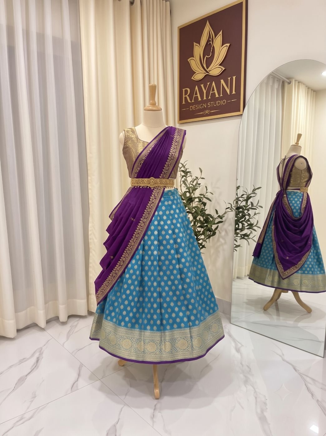 Turquoise brocade lehenga with a purple draped dupatta and gold waist belt on a mannequin in the Rayani studio